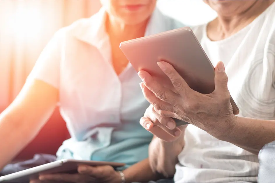 An older couple reading something on a digital tablet.