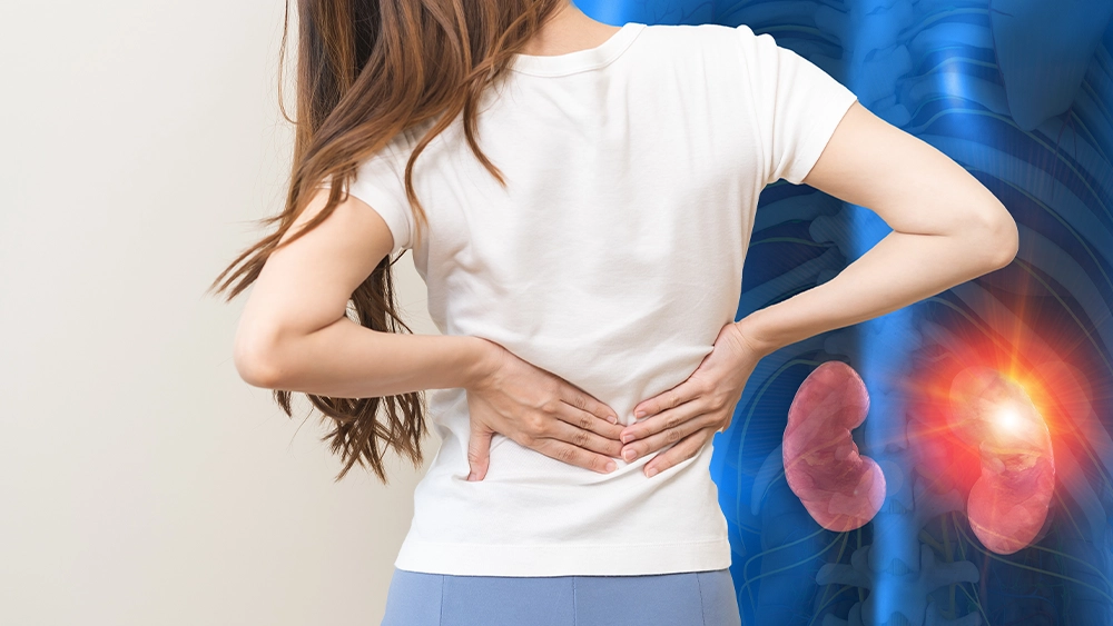 A woman holding holding her back in pain with an x-ray illustration of kidneys.