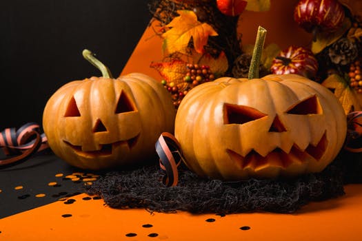 Two jack-o-lanterns surrounded by other Halloween decorations.