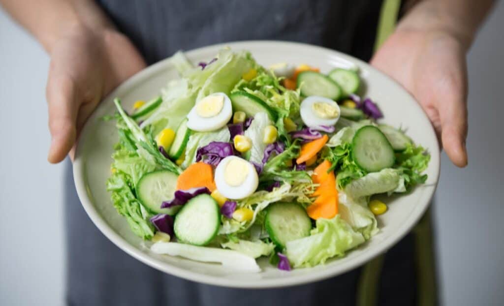 Person holding a bowl of salad.